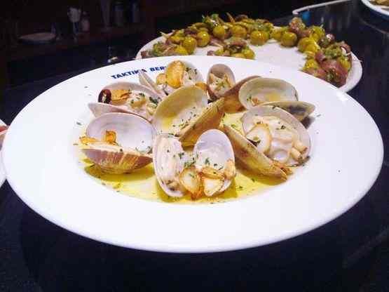 Un plat blanc amb cloïsses i olives a sobre.