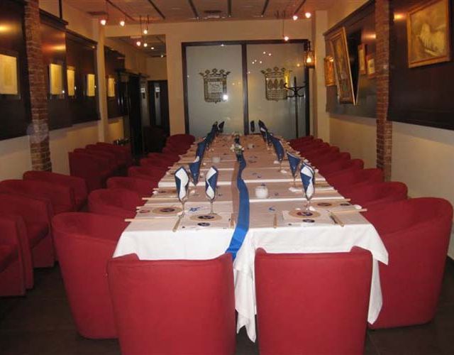 Salón comedor del restaurante con sillas rojas y mesas largas.