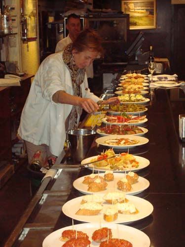Una cocinera preparando pintxos en la barra.